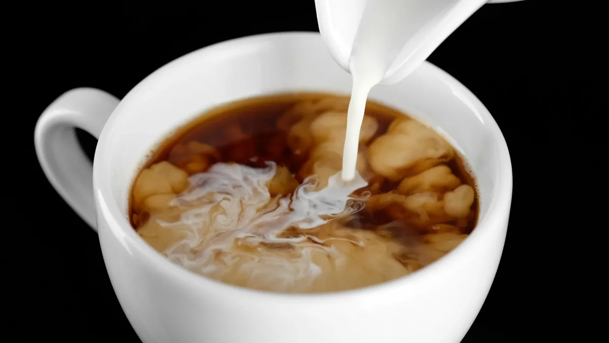Cream being added to coffee. This illustrative photograph does not establish the ingredients or nutritional values of a particular brand.